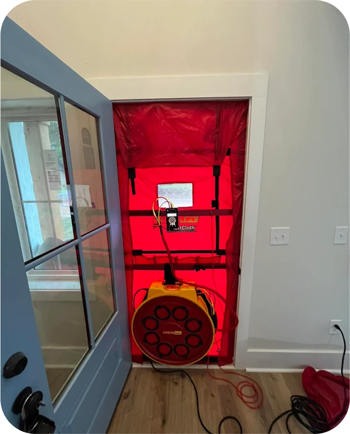 Blower door test setup with red SmartCloth panel and yellow fan mounted in a residential interior doorway